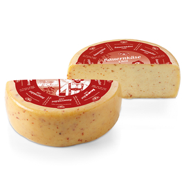Auf dem Bild sind zwei verschiedene Produkte von Bauernkäse zu sehen, darunter ein runder Käse mit einer Chili-Geschmackrichtung und eine Verpackung mit Käseaufschnitt.